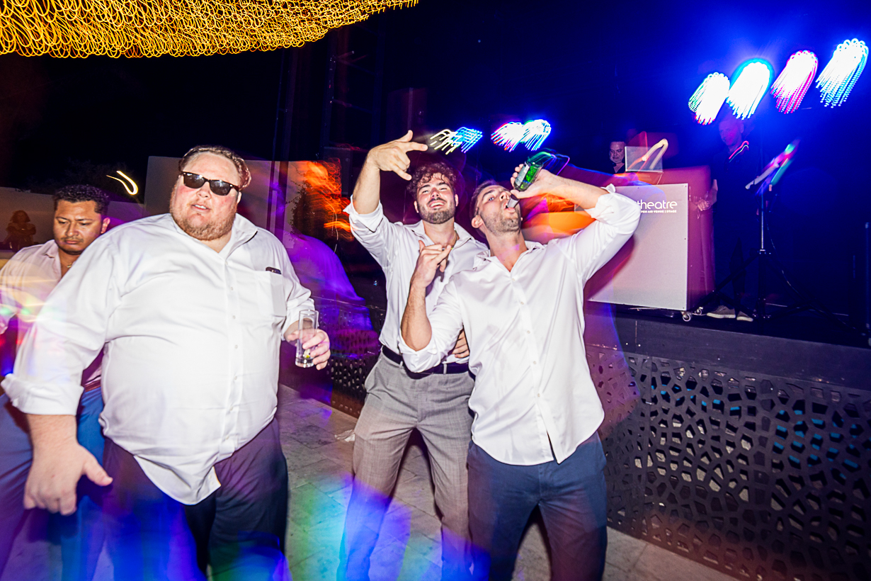 Guests dancing with beers in hand during a lively Greek wedding celebration in Rhodes.
