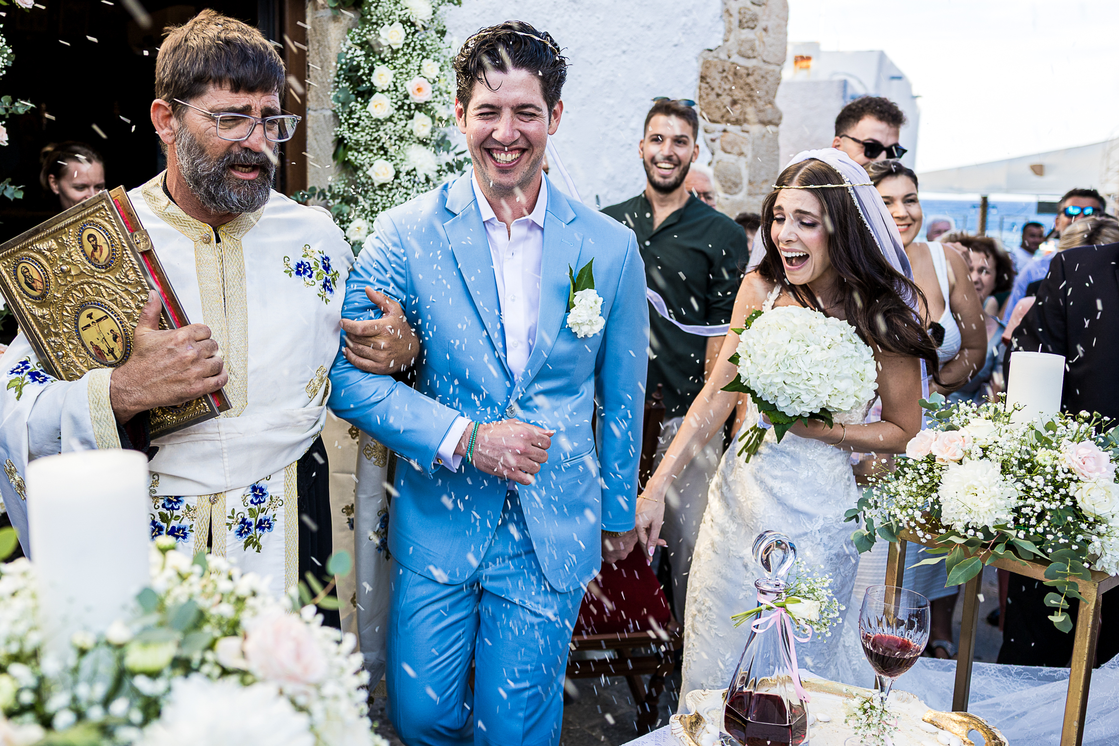 Orthodox wedding in Haraki, Rhodes. Couple dancing the Dance of Isaiah, guests throwinf rice on them