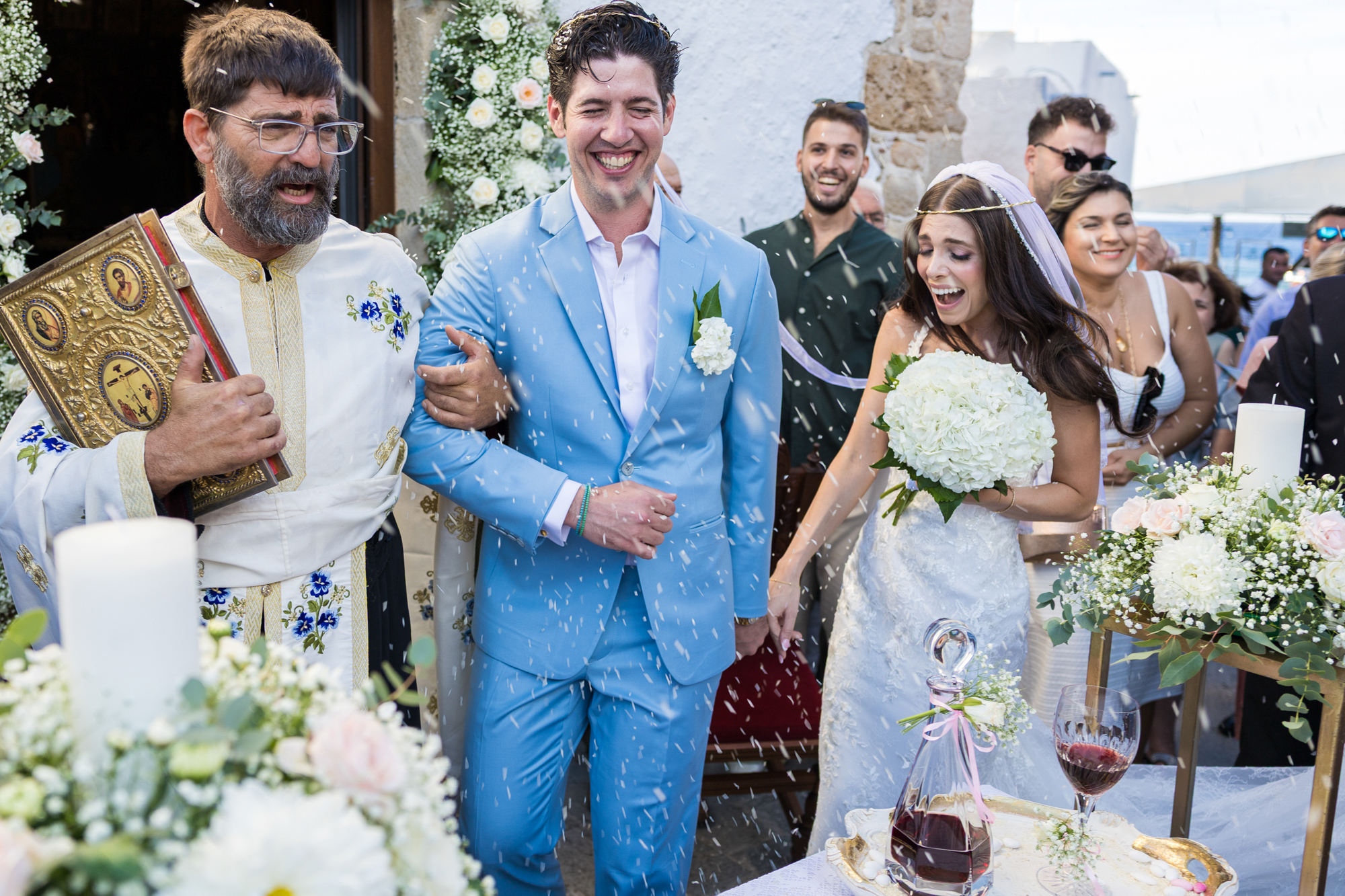 Bride and groom performing the dance of Isaiah as guests throw rice during their Orthodox wedding in Haraki, Rhodes island