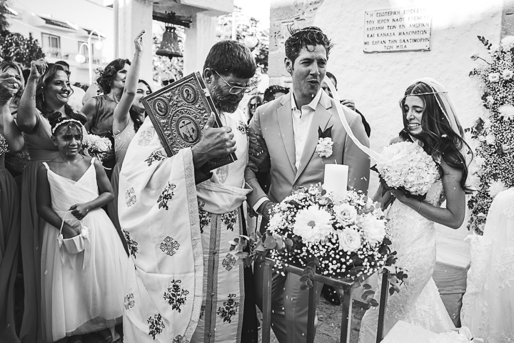 Bride and groom performing the Dance of Isaiah as guests throw rice during their Orthodox wedding in Haraki.