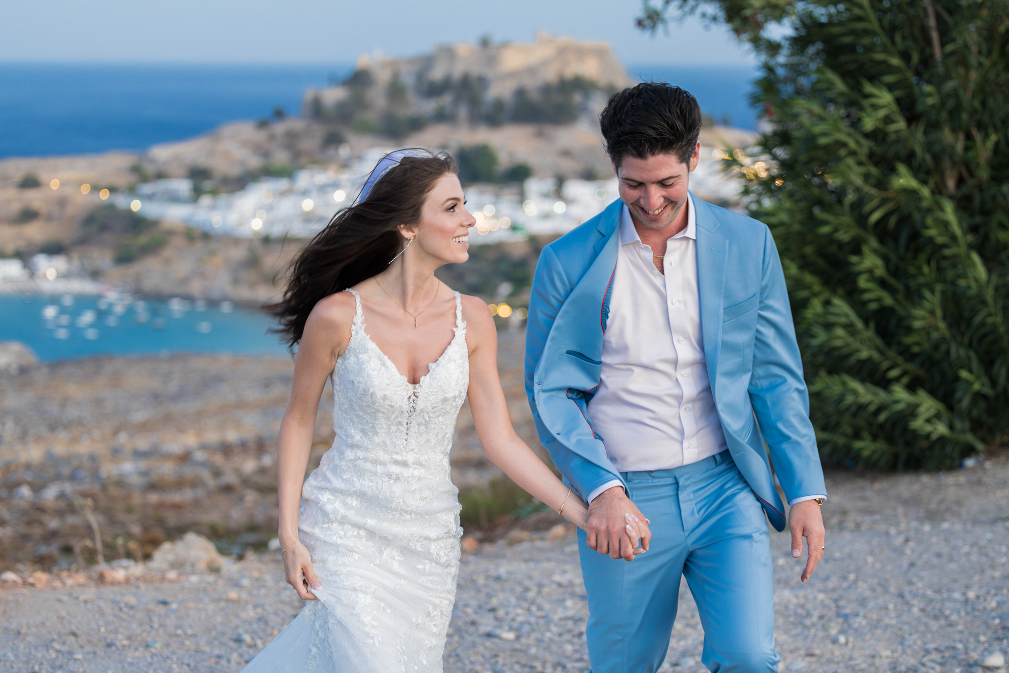 Photo of the newlyweds during their post-ceremony wedding photoshoot in Lindos, Rhodes, with the view of Acropolis.
