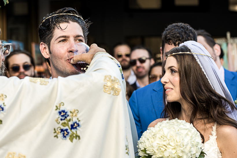 Groom drinking communion wine from the shared cup during a Greek Orthodox wedding ceremony in Rhodes.